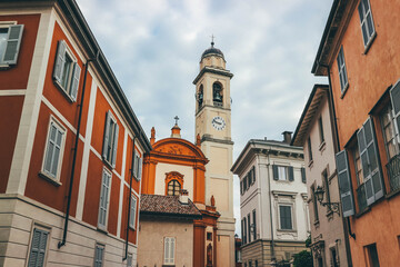 main village church bell tower with old houses in the old town italian style architecture colorful facades over cloudy day in como italy
