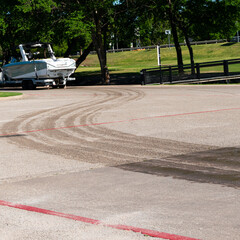 A white an grey boat in the distance following a trail of wet tire marks from recently pulling the...