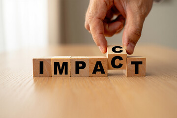 Hand places final letter to spell out the word impact