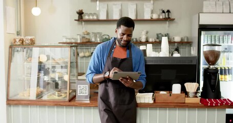 Café barista tapping tablet screen and activating animated order icons floating above display case - Powered by Adobe