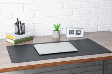 Stylish workplace with laptop and black mousepad on wooden table indoors