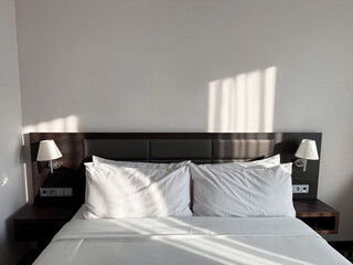Comfortable bed with soft pillows and lamps in hotel room