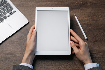Woman with tablet at wooden table, above view