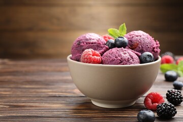 Delicious sorbet with fresh berries and mint in bowl on wooden table against brown background, closeup. Space for text