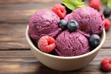 Delicious sorbet with fresh berries and mint in bowl on wooden table, closeup