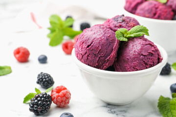 Delicious sorbet in bowl, fresh berries and mint on white marble table, closeup