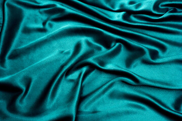 Abstract wavy green silk fabric with glossy folds, elegant background for design.