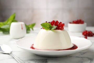 Delicious panna cotta with red currants, sauce and mint on white marble table against blurred background, closeup