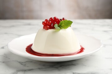 Delicious panna cotta with red currants, sauce and mint on white marble table against blurred background, closeup
