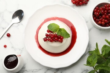 Delicious panna cotta with red currants, sauce and mint on white marble table, flat lay