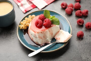 Delicious panna cotta with berries, sauce and mint on grey textured table, closeup