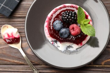 Delicious panna cotta with berries, jam and mint on wooden table, flat lay