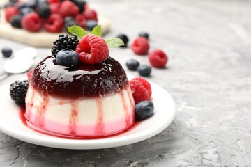 Tasty panna cotta with berries and jam on light grey table, closeup. Space for text