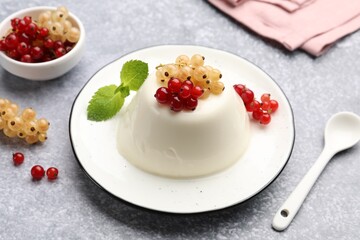 Tasty panna cotta with currants and mint on light grey table, closeup