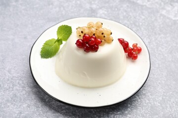 Tasty panna cotta with currants and mint on light grey table, closeup