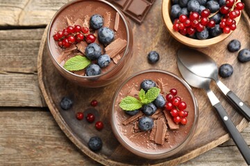 Delicious panna cotta with chocolate, berries and mint on wooden table, top view