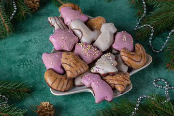Traditional German gingerbread in multi-colored glaze on plate in the shape of Christmas tree on green background