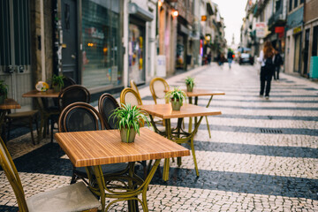Charming Outdoor Cafe Setting with Rustic Tables and Chairs on a Picturesque Cobblestone Street