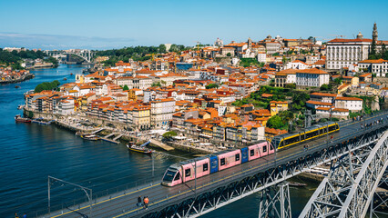 Obraz premium Scenic View of Porto Cityscape with Metro Train Crossing Iconic Bridge Over Douro River in Portugal