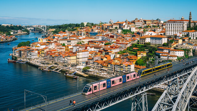 Scenic View of Porto Cityscape with Metro Train Crossing Iconic Bridge Over Douro River in Portugal