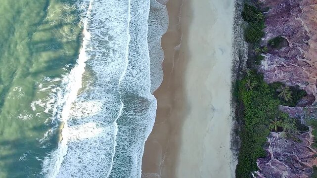 Stunning aerial top-down zenith view of Pipa Beach, Praia de Pipa, in Rio Grande do Norte, Brazil. The beautiful coastline features turquoise ocean waves, a sandy shore, and rocky cliffs.