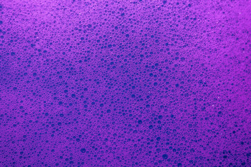 Macro of dyed soap foam with layered colors and airy bubbles, offering a clean, vibrant, and textured surface.