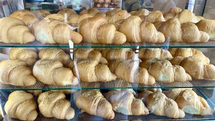 Fresh croissants with sesame seeds on display shelves