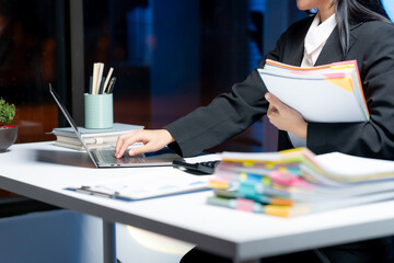 Focused work at office: A professional individual deeply immersed in their office setting, working diligently on a laptop. with organized documents to achieve targets and goals