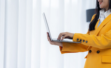 Young woman working with laptop: A confident woman in a yellow blazer, absorbed in her work on a...