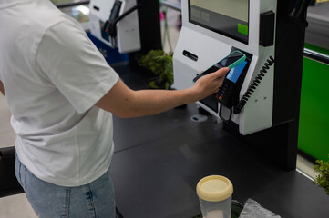 A woman pays using her smartphone at a self-checkout. 