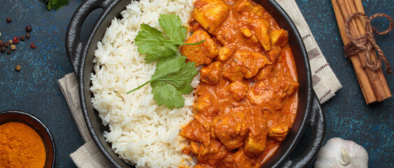 Indian chicken tikka masala in a creamy tomato sauce, served with basmati rice, fresh coriander and spices, traditional dish of India top view