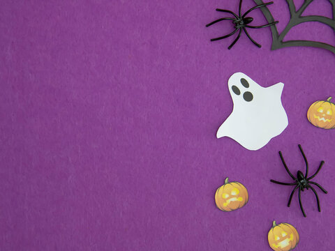 The word Halloween and spiders and ghosts on a purple background