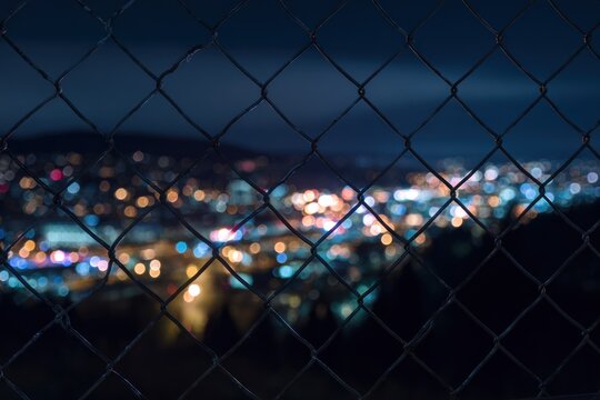 Night city lights through chain-link fence - Powered by Adobe