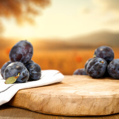 Seasonal fruit of plums on wooden table. Empty copy space  for product placement or text. Golden fall sky with warm and earthy tones.