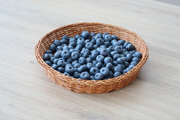 Fresh blueberries in a woven basket, fresh produce and rustic food styling.