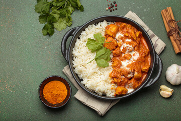 Aromatic Indian chicken tikka masala served with rice and coriander, turmeric, garlic, cinnamon sticks, traditional dish of India top view, copy space