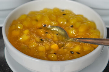 Yellow cooked fruit compote served in a white ceramic bowl, part of buffet.