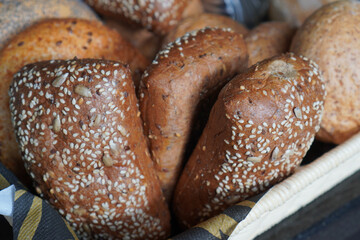 Fresh whole grain bread rolls topped with seeds, arranged on buffet for breakfast.