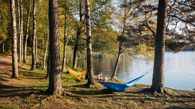 Scenic Lakeside Retreat with Vibrant Hammocks Amidst Serene Forest on a Tranquil Afternoon