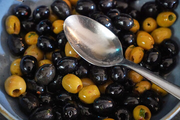 Mixed olives served in bowl with spoon for buffet appetizer or garnish.