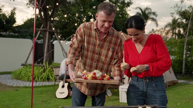 Family all together camp in garden, Old couple cooking BBQ, having a meal. Senior use outdoor camping activity, relax with nature and spend time with young generation cross generation gap. Divergence. - Powered by Adobe