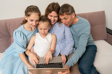 Family Laptop Technology: Family with kids using laptop on sofa at home for entertainment, education.