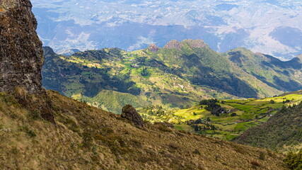 Naklejka premium Panoramic view of a mountain range, valley and small village from the top of the Bolarrumi Rock Complex located on highlands of the Huasipamba community, canton Santa Isabel, Azuay, Ecuadorian Andes