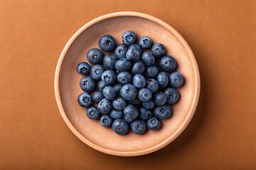 Top view of fresh blueberries on a wooden plate, a healthy and delicious snack, studio shot, overhead view, still life, nobody
