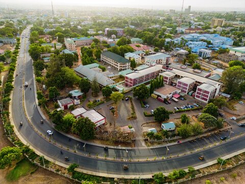 Aerial view of the Government Hospital complex with its red-roofed buildings nestled amid lush greenery and a curving road bustling with vehicles, Lafia Road, Kaduna, Nigeria.