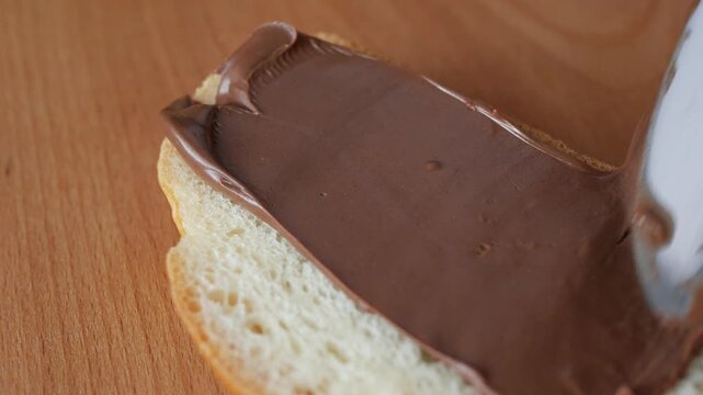Spreading chocolate hazelnut cream on bread slice