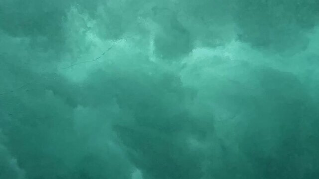Sea wave breaks on shore and forms many air bubbles, underwater view