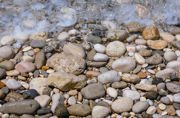 Wet pebbles on a Ionian coast in Agios Gordios resort village on Corfu Island, Greece