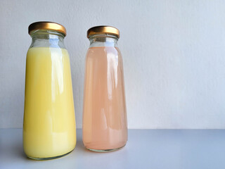 Two bottles of pink and yellow drinks with metal lids