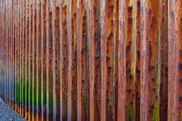An abstract image of a corrugated, rusted metal breakwater. 